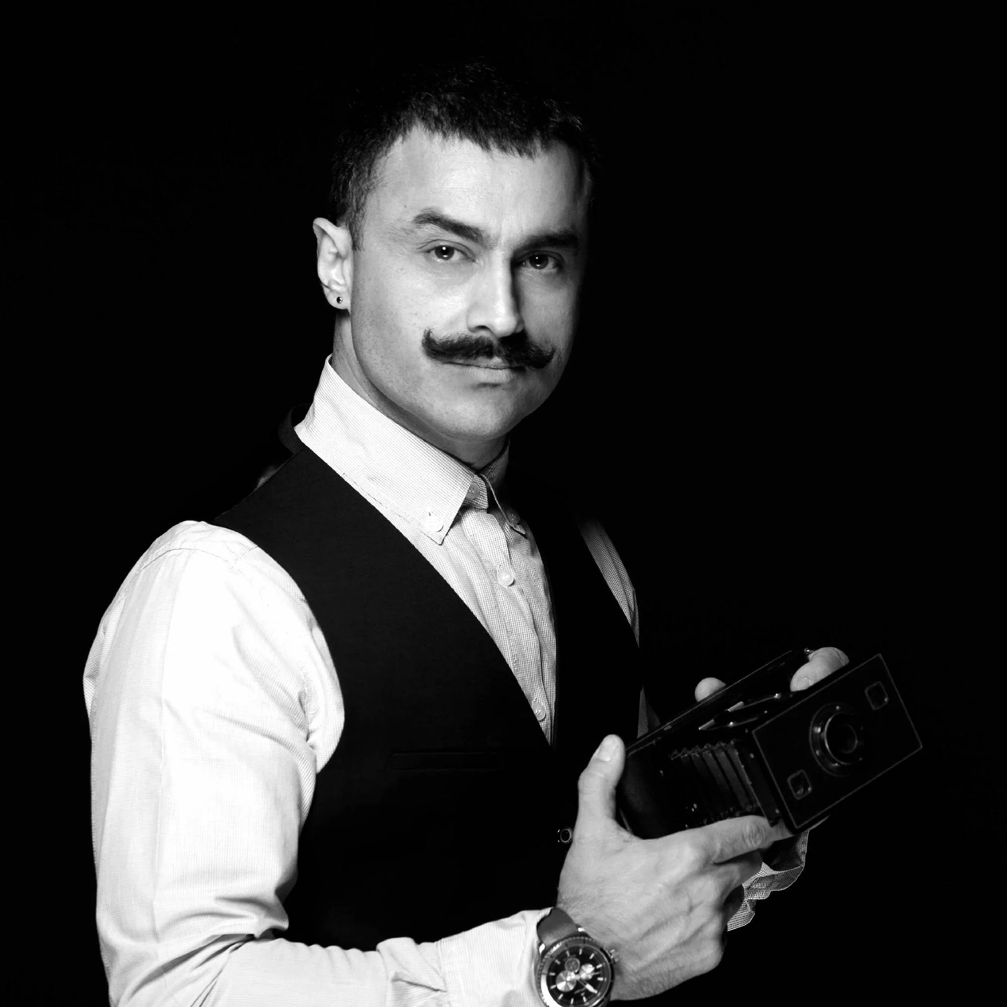 Portrait of Melbourne architectural photographer Selçuk Çınar holding a vintage camera