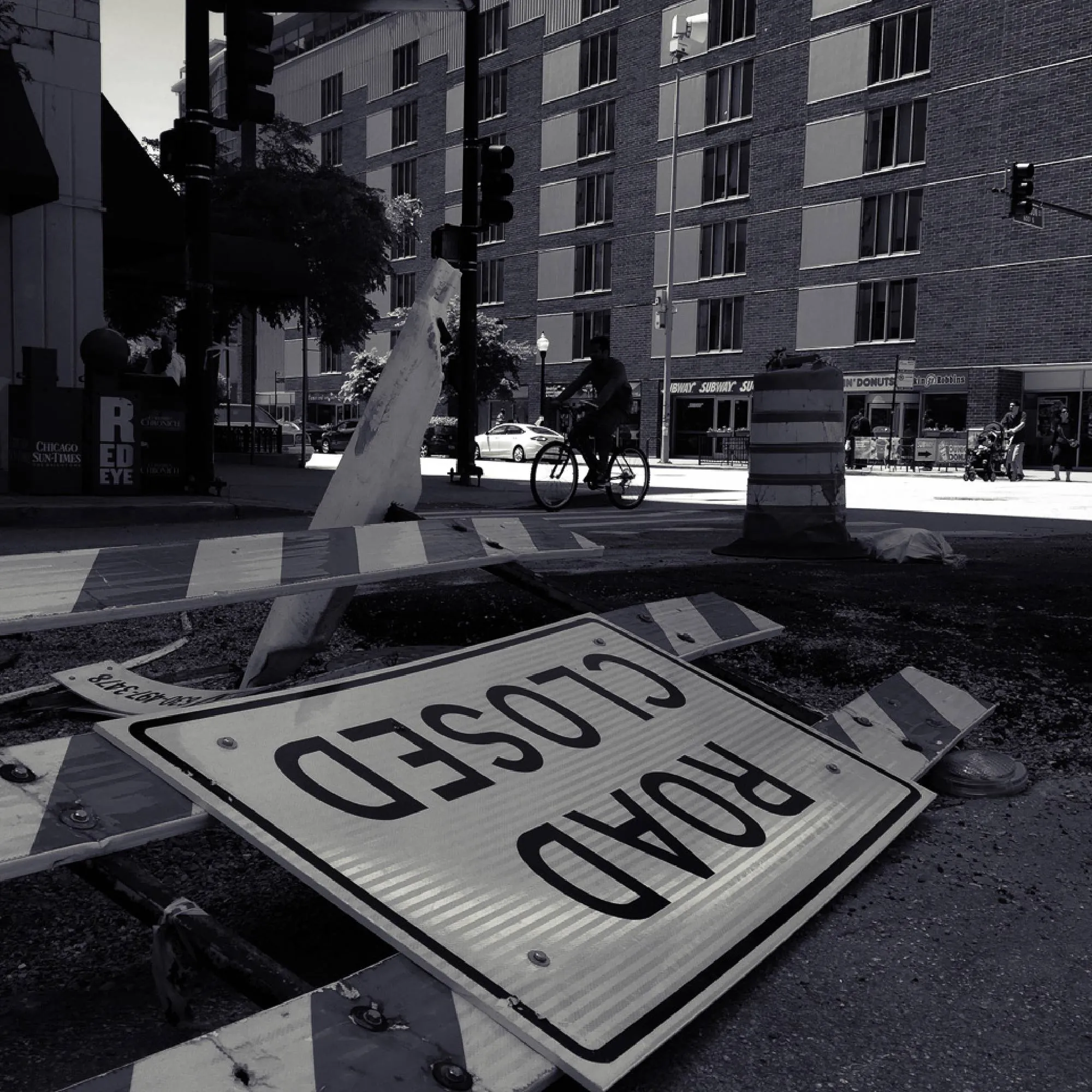 Black-and-white street scene framed by a road-closed sign